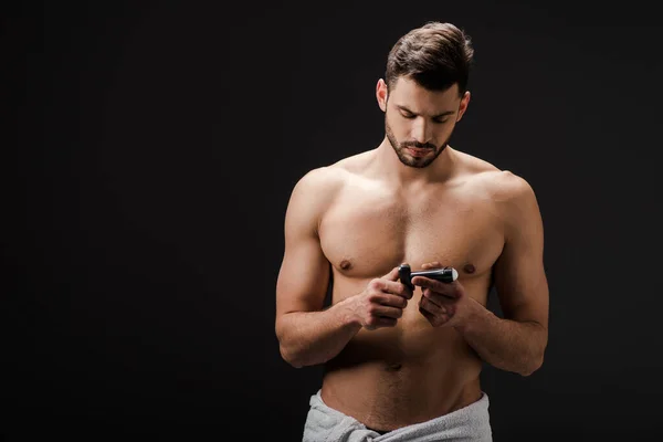 Sexy brunette man looking at deodorant isolated on black — Stock Photo