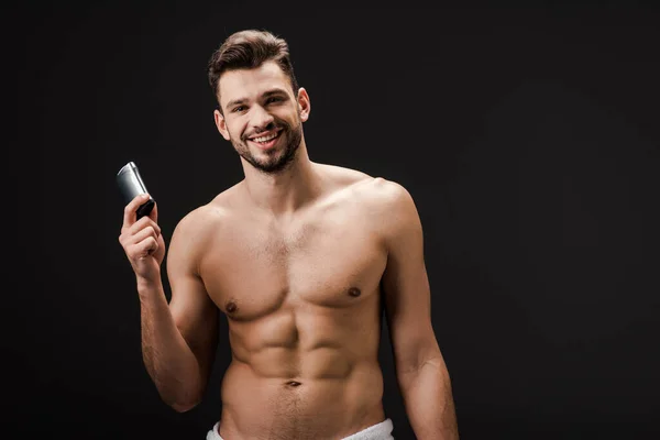 Cheerful sexy man holding deodorant isolated on black — Stock Photo