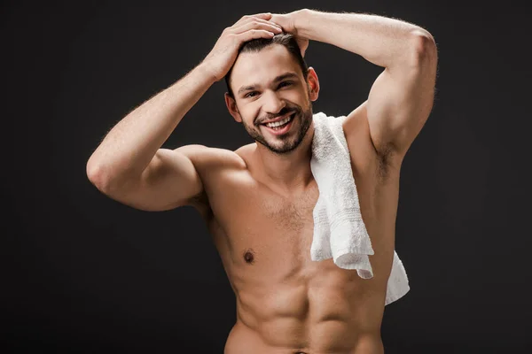 Красивый улыбающийся голый мужчина с полотенцем, изолированным на черном — стоковое фото