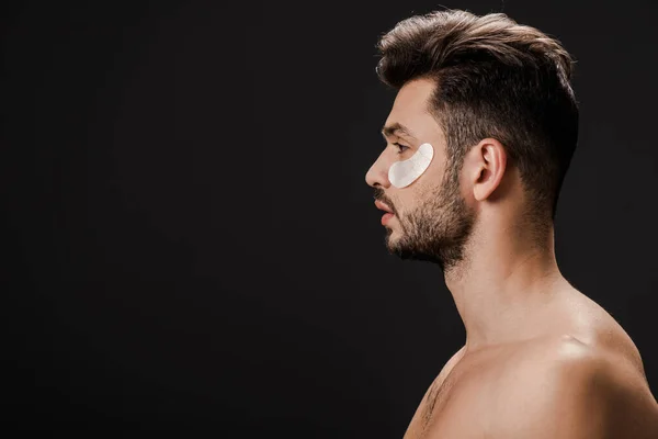 Side view of sexy naked man with eye patches on face isolated on black — Stock Photo
