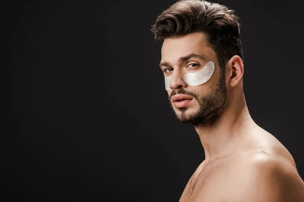 Handsome sexy nude man with eye patches on face isolated on black — Stock Photo