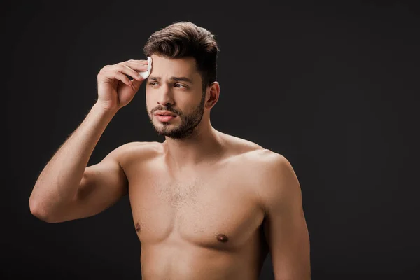 Schöner sexy nackter Mann mit kosmetischen Baumwollpolster isoliert auf schwarz — Stockfoto