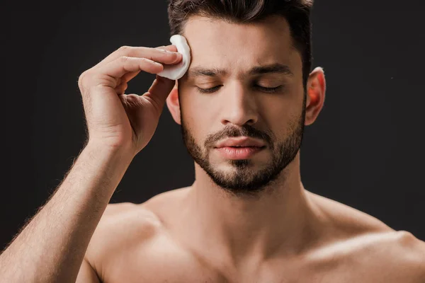 Brunette sexy naked man using cosmetic cotton pad isolated on grey — Stock Photo