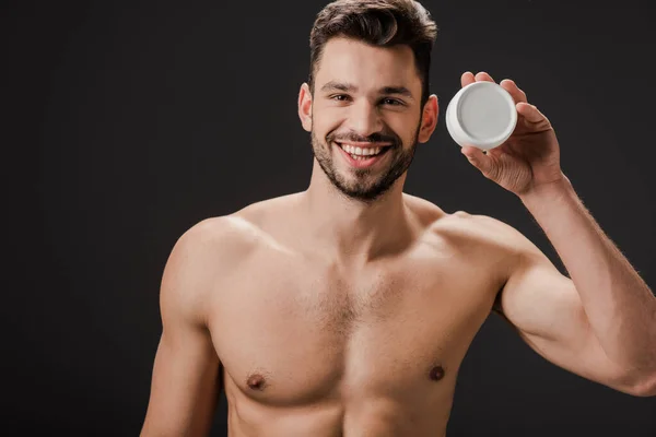 Homme nu souriant tenant récipient en plastique avec crème visage isolé sur gris — Photo de stock