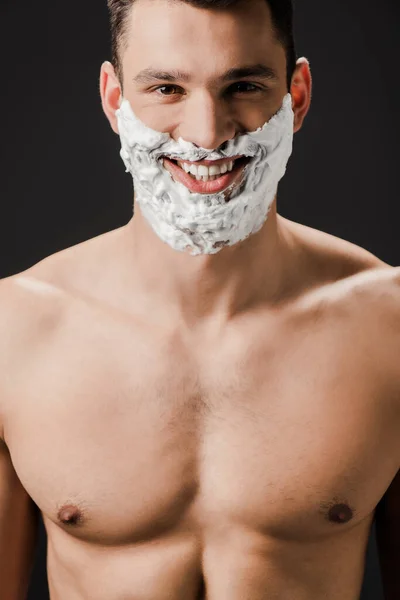 Веселый голый мужчина с пеной для бритья на лице изолированы на черном — стоковое фото