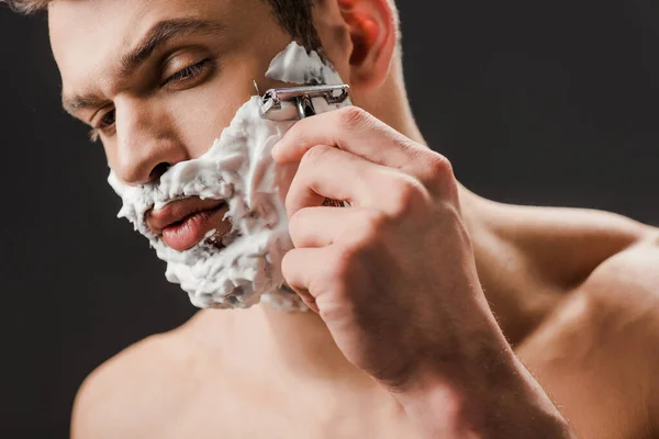 Красивий спокусливий чоловік голиться обличчям з бритвою ізольовано на сірому — стокове фото