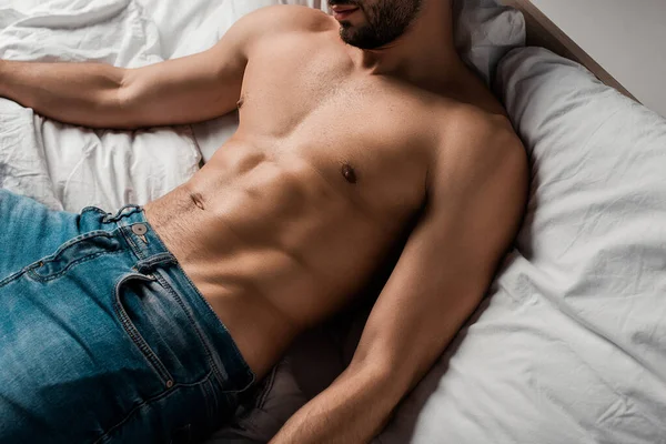 Recortado vista de sin camisa sexy hombre acostado en la cama aislado en gris — Stock Photo