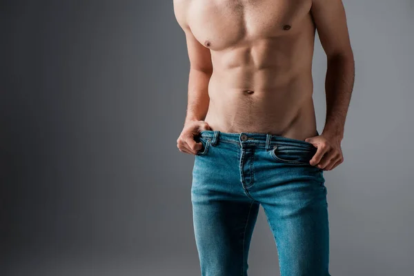 Обрізаний вид сексуального м'язистого чоловіка в джинсах на сірому — Stock Photo