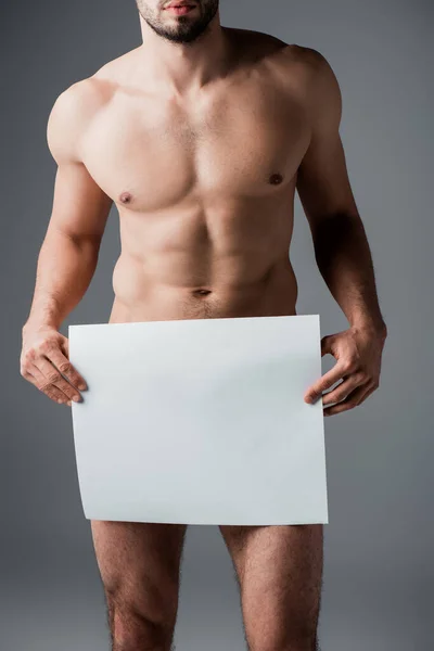 Recortado vista de sexy desnudo macho sosteniendo en blanco cartel aislado en gris - foto de stock
