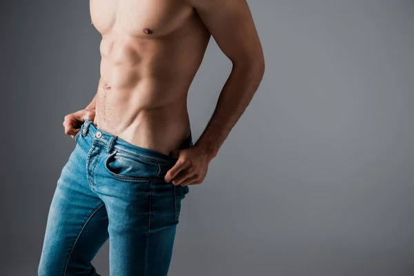 Vista ritagliata di sexy uomo senza camicia in jeans isolato su grigio — Foto stock