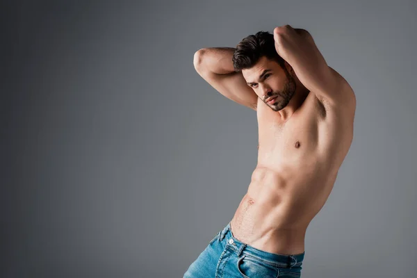 Handsome sexy shirtless man in jeans on grey — Stock Photo