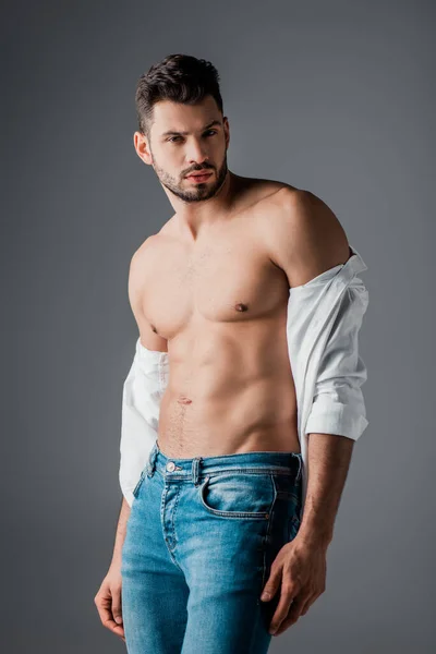 Morena sexy homem no branco camisa e jeans isolado no cinza — Fotografia de Stock