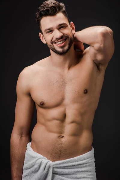 Cheerful sexy muscular man in towel isolated on black — Stock Photo