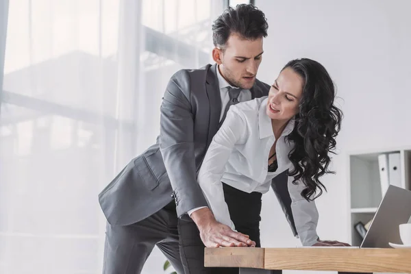 Schöner Geschäftsmann belästigt unzufriedene Sekretärin im Amt — Stockfoto