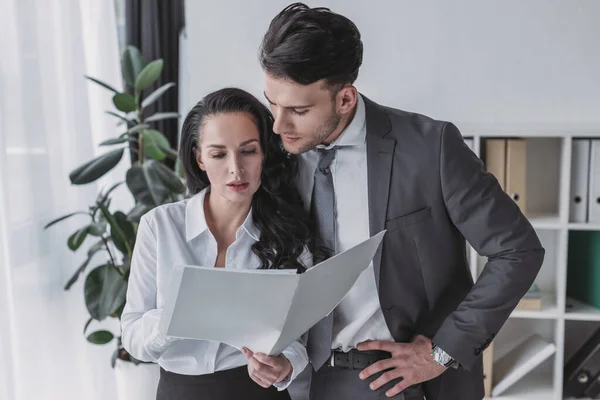Attractive secretary and handsome businessman looking at papers together — Stock Photo