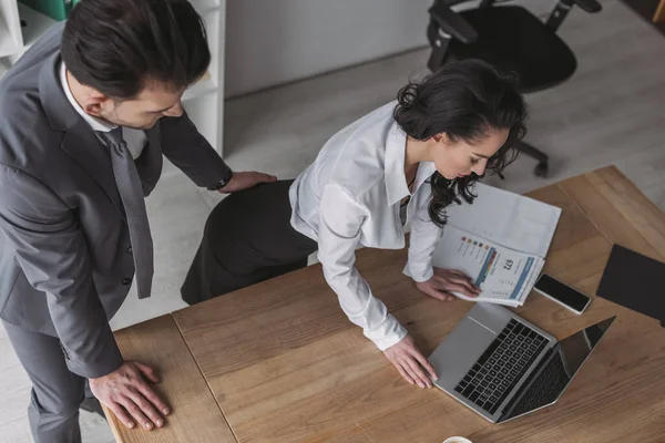 Alto ángulo vista de empresario tocando nalgas de secretario de pie en el lugar de trabajo - foto de stock