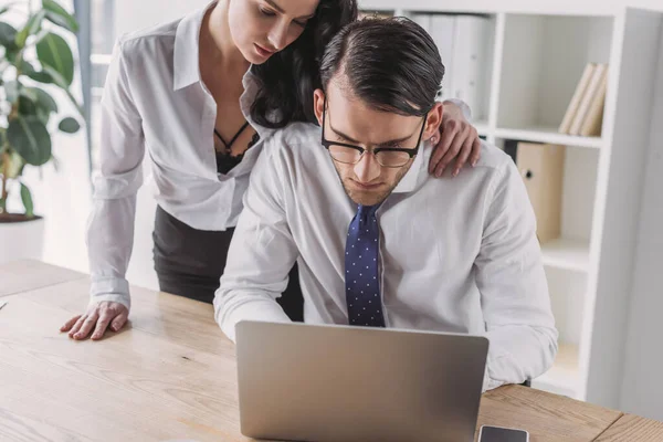 Чуттєва бізнес-леді торкається плеча робочого колеги, спокушаючи його в офісі — стокове фото