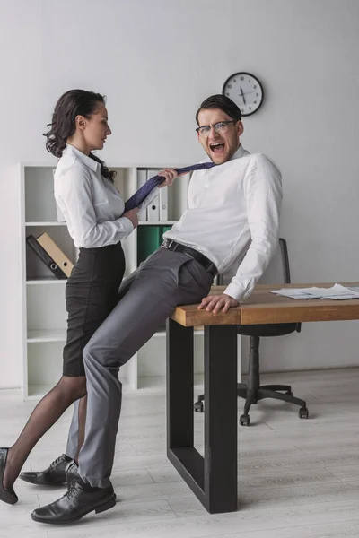 Сексуальная деловая женщина, соблазняющая шокированного коллегу, трогая его галстук — стоковое фото
