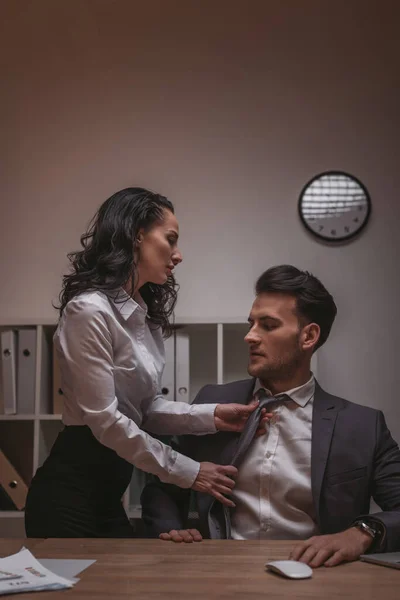 Beautiful, seductive secretary in formal wear touching tie of handsome businessman — Stock Photo