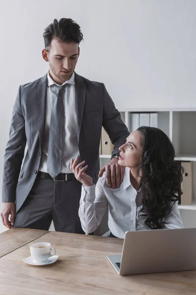 Secrétaire mécontent regardant homme d'affaires toucher son épaule — Photo de stock