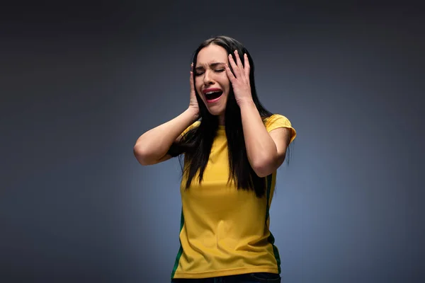 Stressed attractive young woman crying and holding head on grey — Stock Photo