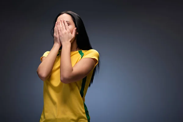 Asustado ventilador de fútbol femenino cubriendo la cara en gris - foto de stock