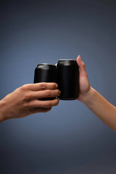 Vista cortada de homem e mulher clinking com latas pretas em cinza — Fotografia de Stock
