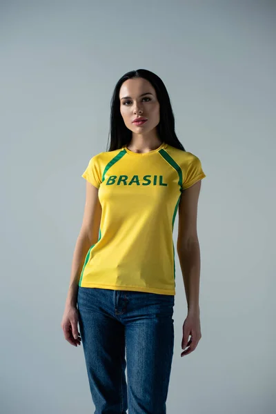 Atractivo abanico de fútbol en camiseta amarilla con signo brasileño aislado en gris - foto de stock