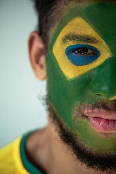 Fã de futebol americano africano com rosto pintado como bandeira brasileira isolada em cinza — Fotografia de Stock