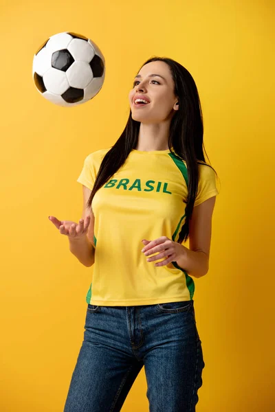 Весела жінка-футболістка кидає м'яч на жовтий — стокове фото