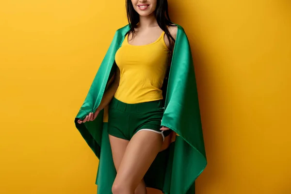 Vue recadrée du fan de football féminin souriant en short tenant le drapeau brésilien sur jaune — Photo de stock