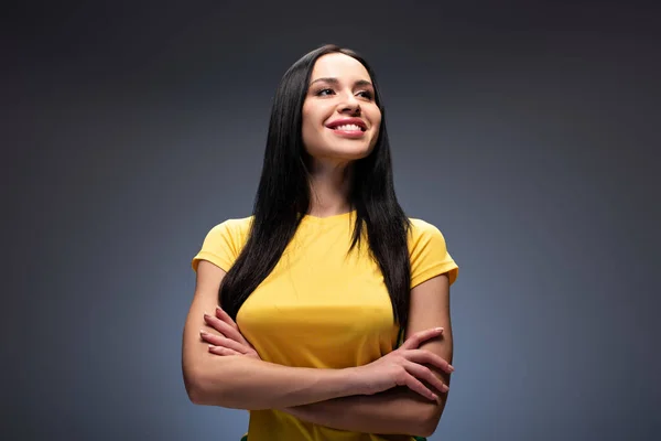 Proud smiling girl standing with crossed arms on grey — Stock Photo