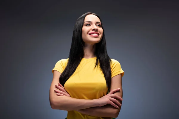 Orgullosa chica sonriente de pie con los brazos cruzados en gris - foto de stock