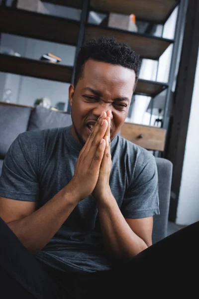 Stressed african american man suffering from panic attack with hands together at home — Stock Photo