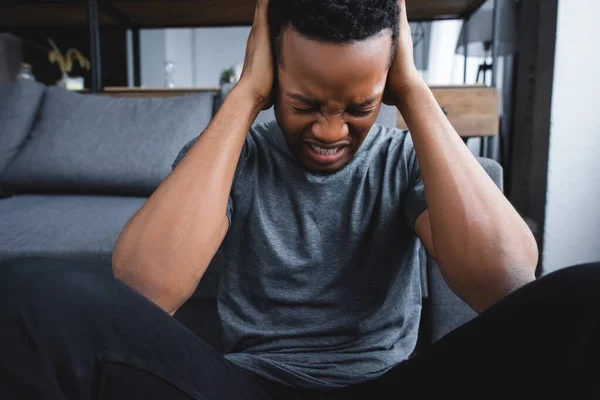 Homem afro-americano estressado tendo cuidados de saúde enquanto sofre de ataque de pânico em casa — Fotografia de Stock