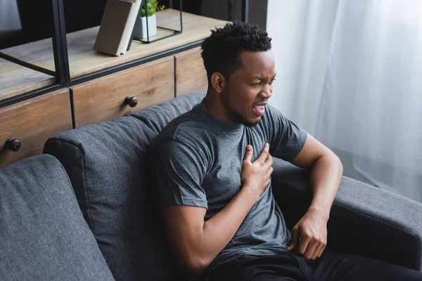 Stressed african american man having heart attack at home — Stock Photo