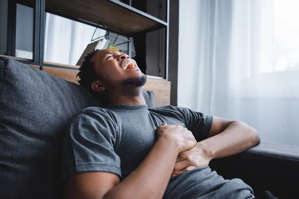 Hombre afroamericano estresado teniendo un ataque al corazón en casa - foto de stock