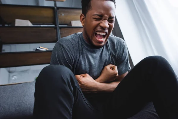 Напряженный африканский американец кричит во время панической атаки дома — стоковое фото
