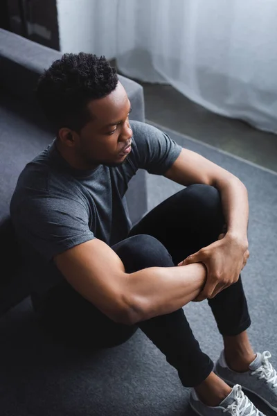 Sad african american man sitting on floor at home — Stock Photo