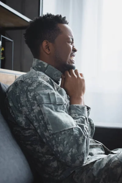 Stressed african american soldier in military uniform suffering from PTSD at home — Stock Photo