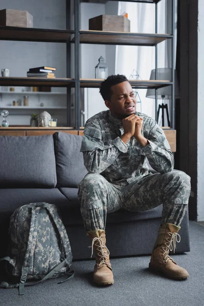Triste soldado afroamericano en uniforme militar que sufre de estrés postraumático en casa - foto de stock