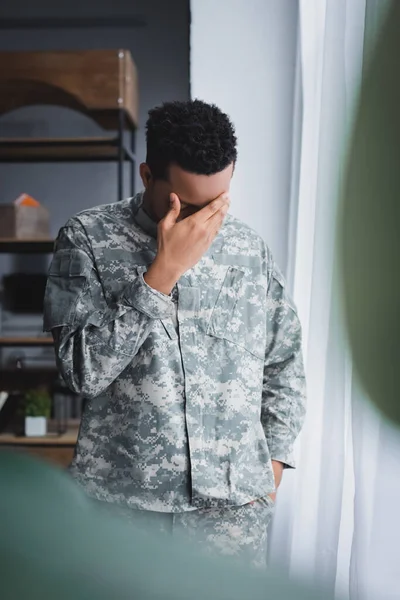 Enfoque selectivo de soldado afroamericano triste solitario en uniforme militar en casa - foto de stock