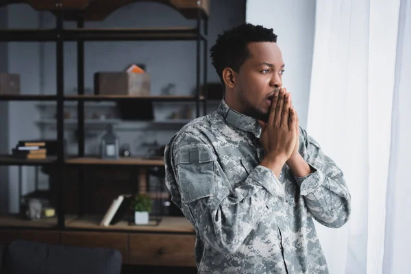 Soldado afroamericano preocupado en uniforme militar en casa - foto de stock