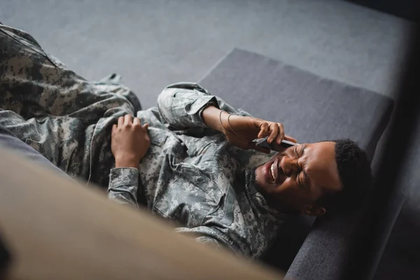 Gestresster afrikanisch-amerikanischer Soldat in Militäruniform weint, während er mit dem Smartphone spricht und zu Hause an PTBS leidet — Stockfoto