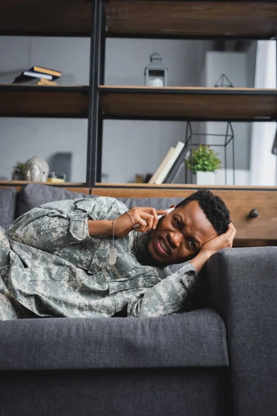Soldado afro-americano estressado em uniforme militar chorando enquanto falava em smartphone e sofrendo de TEPT em casa — Fotografia de Stock