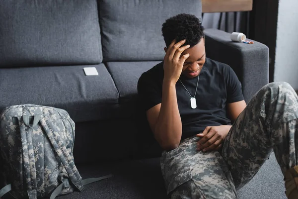 Stressed african american soldier with army badge suffering from PTSD at home — Stock Photo