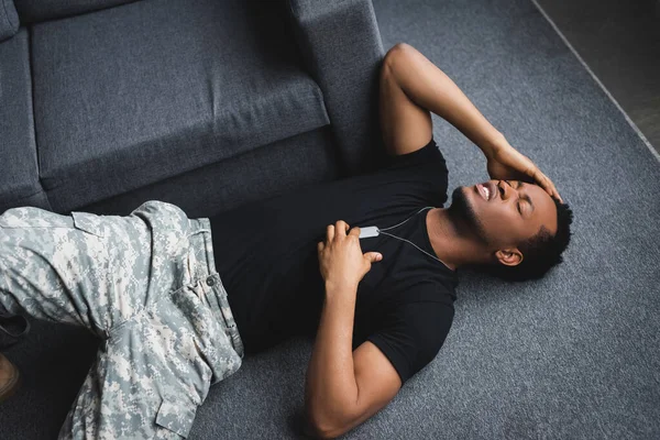 Soldato afroamericano stressato con distintivo dell'esercito che ha un attacco di cuore a casa, affetto da PTSD — Foto stock