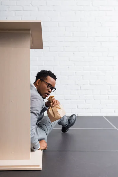 Nervous african american speaker with paper bag having panic attack during business conference in office — Stock Photo