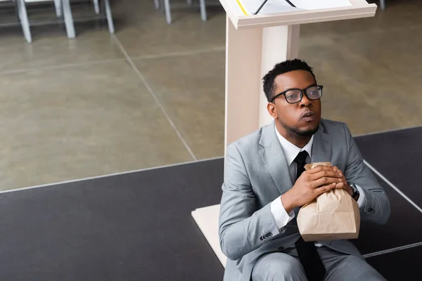 Nervous african american speaker holding paper bag and having panic attack before business conference — Stock Photo