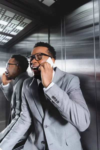 Souligné homme d'affaires afro-américain pleurer et parler sur smartphone tout en souffrant d'une attaque de panique dans l'ascenseur — Photo de stock